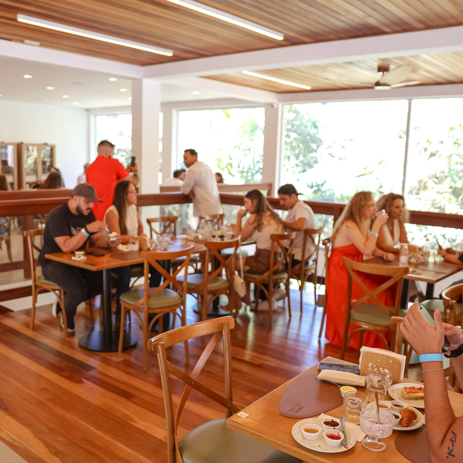 Mezanino do Frutta e Crema Lounge com mesas de madeira e vista para o jardim